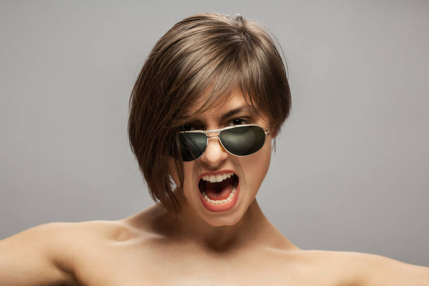 Beautiful girl fashion portrait wearing sunglasses. Surprised angry screaming face expression. - Photo, image