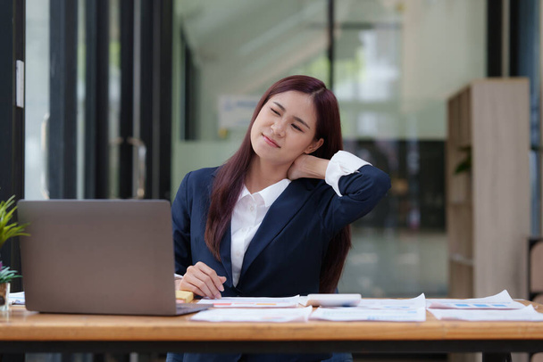 Afbeelding van Aziatische zakenvrouw verlichten pijn haar nek lijden aan zittend werk. kantoor syndroom concept - Foto, afbeelding