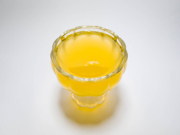 Orange flavored drink in glass cup on white background - Фото, зображення