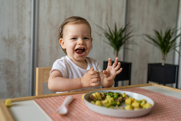 Uma menina pequena criança caucasiana comendo enquanto se senta na mesa sozinha no espaço de cópia em casa criança pequena almoçando refeição saudável no quarto no dia sorriso feliz - Foto, Imagem