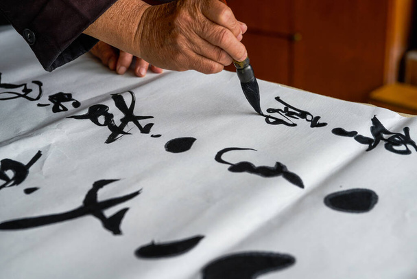 Un vieux calligraphe écrit et crée des œuvres de calligraphie. Traduction : Il pleut sur l'étang avec un léger tonnerre à l'extérieur de Liuwai, et le bruit de la pluie tombe et brise le lotus. - Photo, image