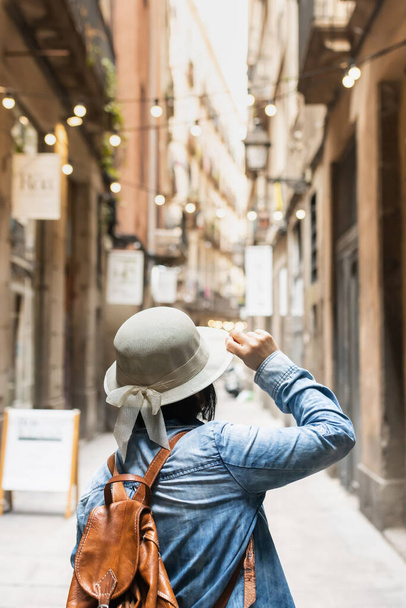 Latin tourist on vacation holding the cap in the Gothic Quarter of Barcelona (Spain), travel concept. - Foto, immagini