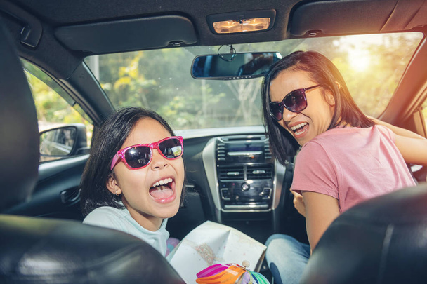 Rodinná dovolená, šťastná rodina na výletě autem, máma řídí auto, zatímco její dcera sedí vedle, máma s dcerou cestují. letní jízda automobilem. - Fotografie, Obrázek