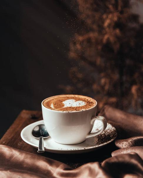 A vertical close-up shot of a beautiful cup of cappuccino with romantic latte art. - Fotó, kép
