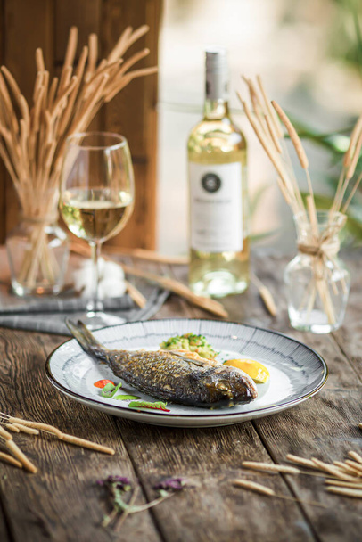 Piatto di pesce gourmet alla griglia con vino bianco su sfondo di legno - Foto, immagini