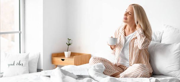 Ранок красивої зрілої жінки п'є каву в спальні
 - Фото, зображення