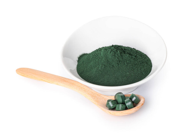 Bowl of spirulina powder and spoon with pills on white background - Foto, imagen