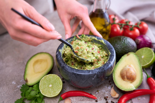 making guacamole - woman holding spoon with mixed minced ingredients. - Foto, Imagem