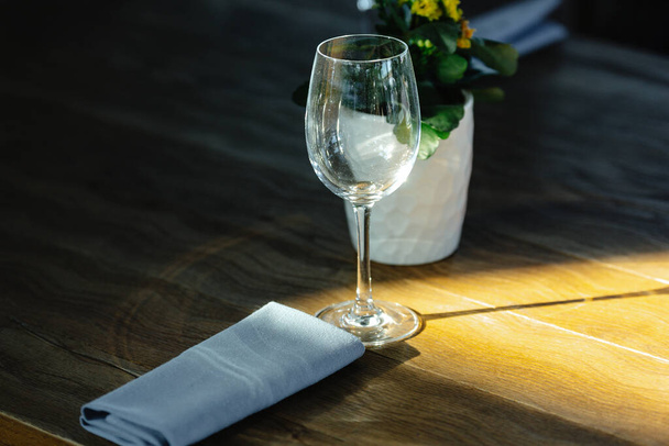 a glass in a restaurant stands on a table in a ray of sunlight. Served dinner table in a restaurant. Restaurant interior - Foto, Bild