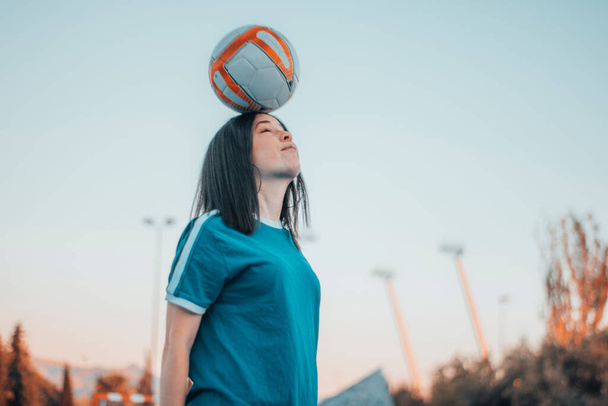 A beautiful female playing football and hitting the ball with head - Fotoğraf, Görsel