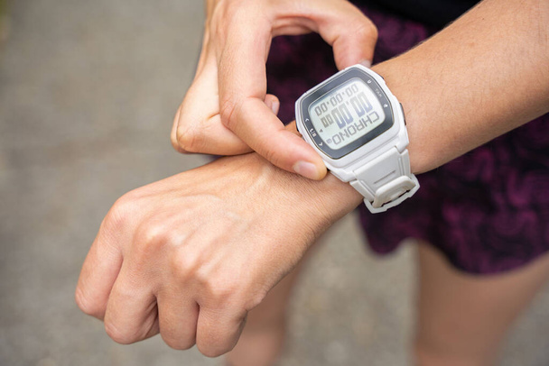 A young athletic female using a fitness tracker or watch before running training outdoors - Photo, Image