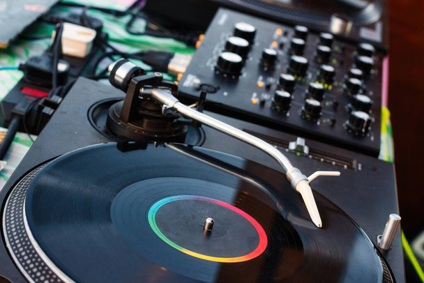 Vinyl record on a deejay's turntable with mixing desk equipment sound system - Fotografie, Obrázek