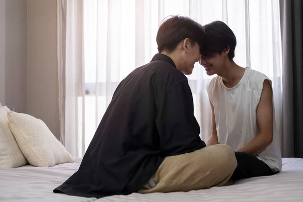 Romantik genç eşcinsel çift rahat bir yatakta oturuyor. LGBT topluluğu, eşit haklar, güzellik ve sevgi. - Fotoğraf, Görsel