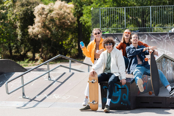 boldog és stílusos többnemzetiségű barátok nézi kamera korcsolyapark - Fotó, kép
