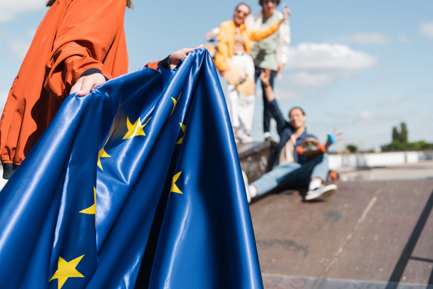 vista parziale della donna con bandiera dell'unione europea vicino agli amici offuscati all'aperto - Foto, immagini