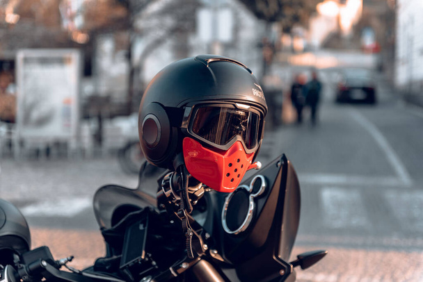 A closeup of the black helmet on a motorcycle parked in the street. Selected focus. - 写真・画像