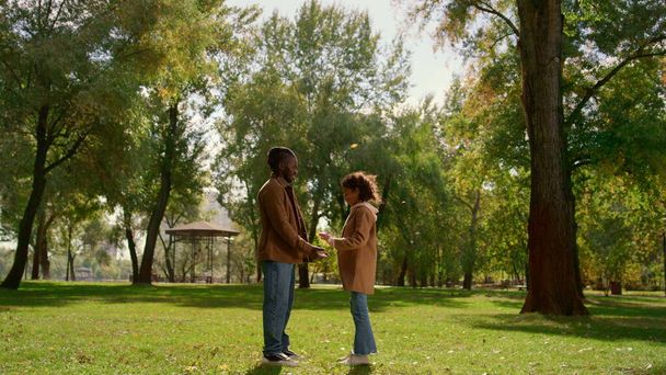 Baba kızının elini tutup alnına dokunuyor. Duygusal bağ kuran çocuk baba. Afrikalı Amerikan ailesi sonbahar parkında dinleniyor. Kibar ebeveyn şehir bahçesinde samimi sevgi gösterisi yapıyor.. - Fotoğraf, Görsel