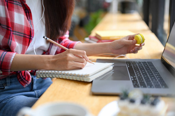 Kesilmiş resim, genç Asyalı üniversite öğrencisi ev ödevini yapıyor, günlük yazıyor, online bir derse katılıyor ve kafede defter dersi veriyor.. - Fotoğraf, Görsel