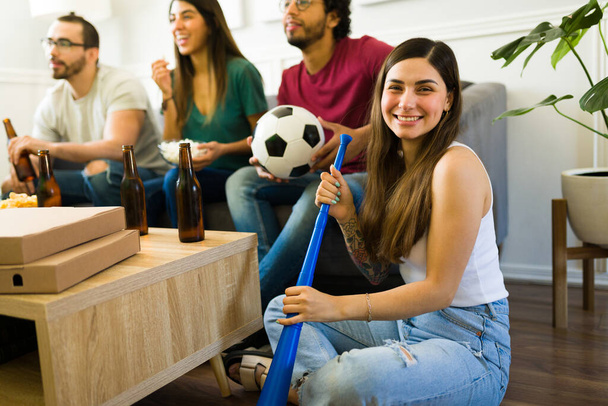 Kaunis onnellinen nainen hymyilee ja pitää vuvuzela taas hengailla ystävien kanssa katsomassa urheilua  - Valokuva, kuva