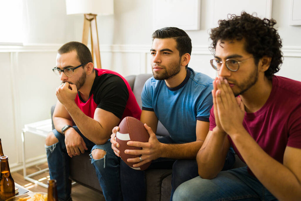 Přátelé se obávají o svůj sportovní tým při sledování fotbalového utkání v obývacím pokoji - Fotografie, Obrázek