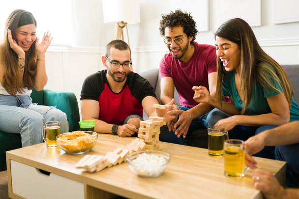 Houkutteleva erilaisia ystäviä nauraa ja tunne onnellinen pelatessaan torni lautapeli juhlissa - Valokuva, kuva