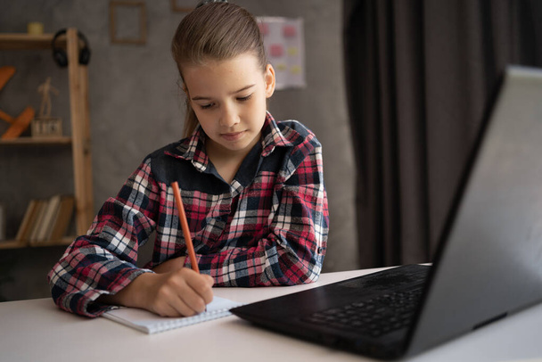Gülümseyen küçük kız el yazısı çalışması, evde dizüstü bilgisayar kullanımı, küçük çocuk internet dersi veya bilgisayar dersi alıyor, evde eğitim kavramı - Fotoğraf, Görsel