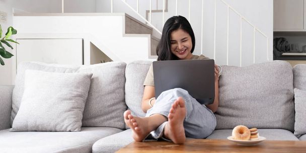 aziatische jonge vrouw op zoek laptop lachen met goed nieuws of kortingsbon voor het winkelen online thuis.Happy en vrolijke vrouw op zoek naar laptop gelezen bericht voel opwinding - Foto, afbeelding