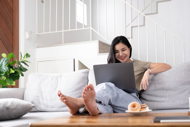 asiatische junge Frau auf der Suche Laptop lachen mit guten Nachrichten oder Rabattgutschein für Online-Shopping zu Hause. Glückliche und fröhliche Frau auf dem Laptop lesen Nachricht fühlen sich erregt - Foto, Bild