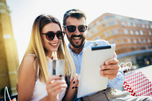 Casal jovem usando cartão de crédito e tablet digital para compras on-line ao ar livre. - Foto, Imagem
