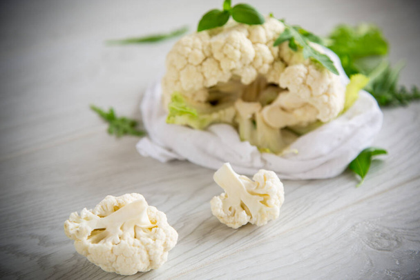 inflorescences of small raw cauliflower on a light wooden table - Foto, Bild