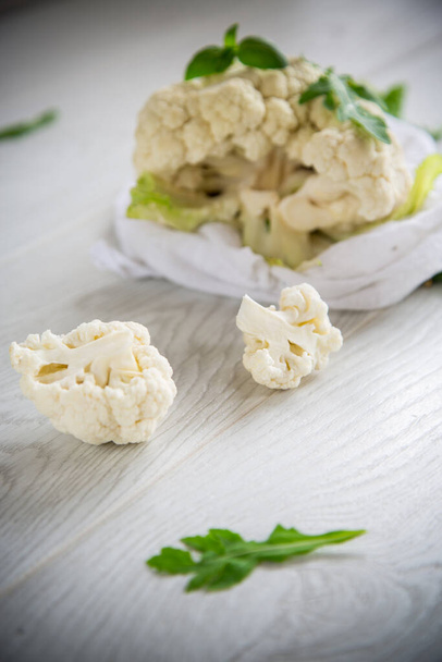 inflorescences of small raw cauliflower on a light wooden table - Foto, Bild
