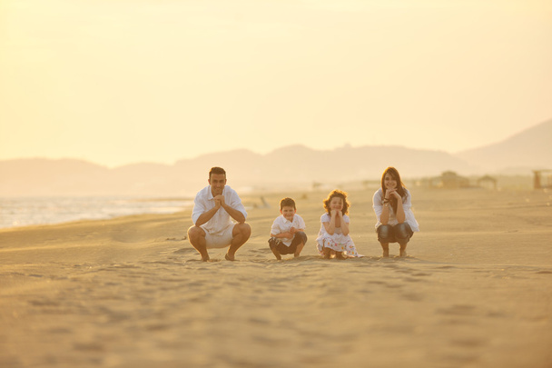 Щаслива молода сім'я розважається на пляжі на заході сонця
 - Фото, зображення