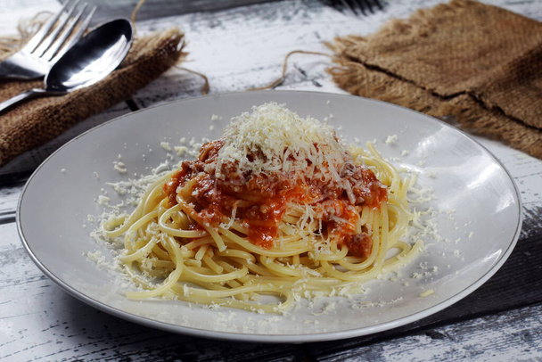 A closeup of a plate of spaghetti with meat sauce and  grated cheese on top - Fotoğraf, Görsel