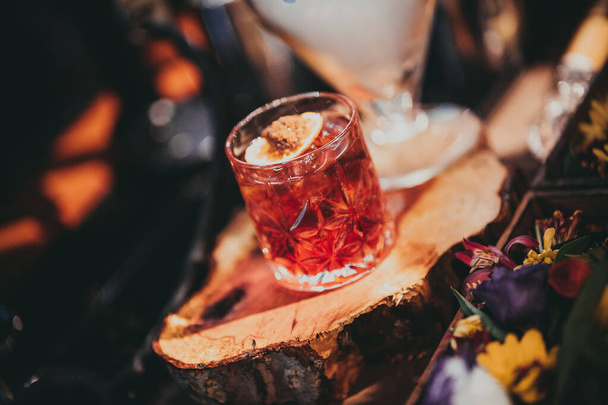A close-up shot of a Negroni cocktail on a cross-section of a tree trunk. - Zdjęcie, obraz