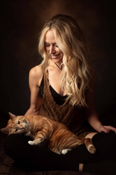 A vertical shot of a young Caucasian female with a cat lying on her knees - Фото, изображение