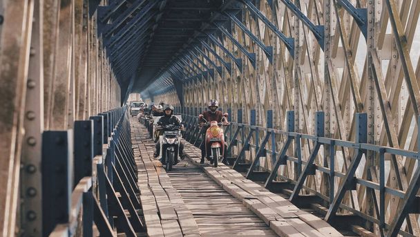 Молоді люди їздять на мотоциклах, коли перетинають міст Сірахонґ. Індонезія. - Фото, зображення