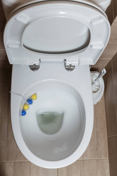 toilet bovenaanzicht. open toilet met schoonmaakballetjes. luchtverfrisser en toiletschoonmaakmiddel. - Foto, afbeelding