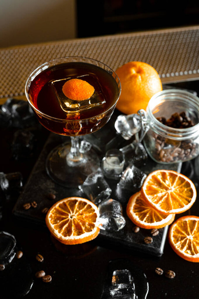 Glass of cocktail with whisky and orange liquor with barrel on background - Фото, изображение