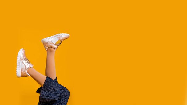 childrens feet in shoes on a yellow background, copy space - Photo, Image