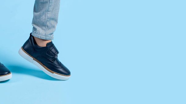 childrens feet in sneakers on a blue background. copy space - Foto, afbeelding