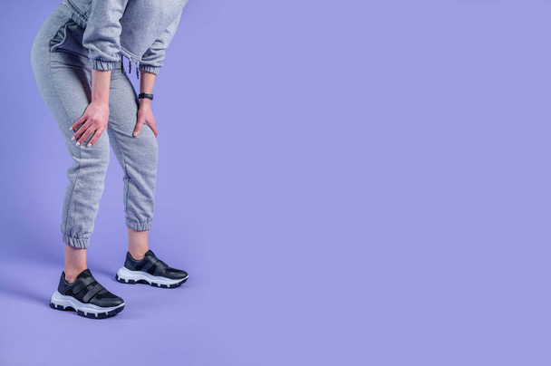 womens feet in sports shoes on a purple background. copy space - Fotó, kép