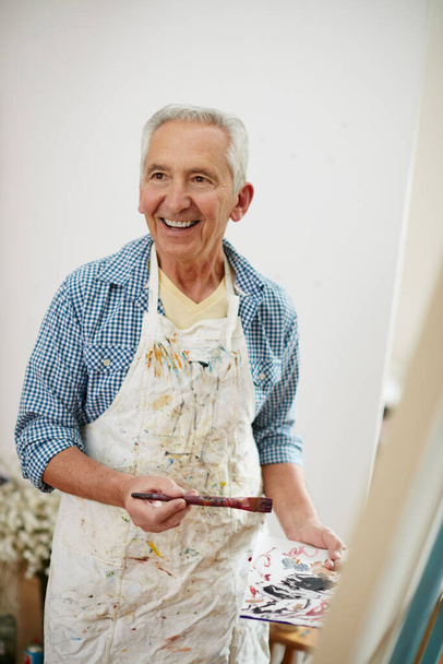 Shot of a senior man working on a painting at home. - Foto, imagen