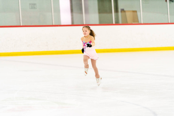小さな女の子練習フィギュアスケート上の屋内アイススケートリンク. - 写真・画像