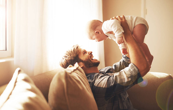 Recorte de un joven padre y su bebé en la sala de estar. - Foto, Imagen