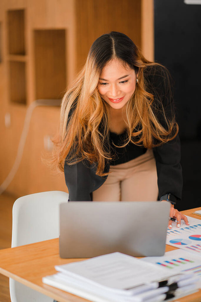 Bizneswoman za pomocą laptopa przy biurku niezależnej firmy czytanie wykresu finansowego Analiza marketingowa planowanie, Azjaci, biuro, pionowy obraz - Zdjęcie, obraz