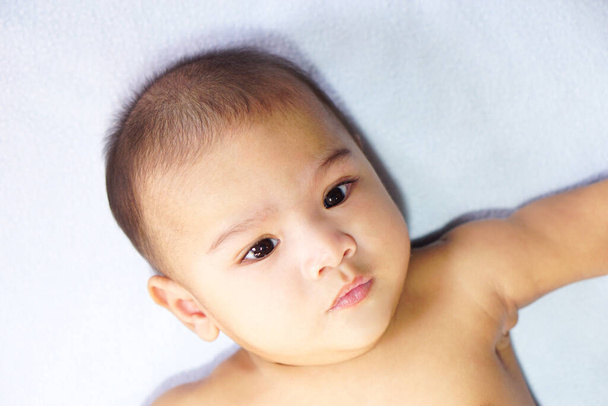 Un petit bébé asiatique mignon (environ 4-6 mois) couché sur le lit bleu. Le concept d'amour, soins, empathie, belle, mignonne, adorable et jolie. - Photo, image