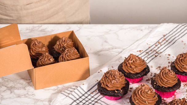 Paso a paso. Envasar cupcakes de chocolate con glaseado de ganache de chocolate en una caja de cupcakes de papel. - Foto, Imagen