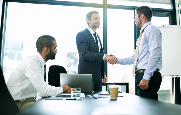 Shot of colleagues shaking hands during a formal meeting in an office. - Photo, Image