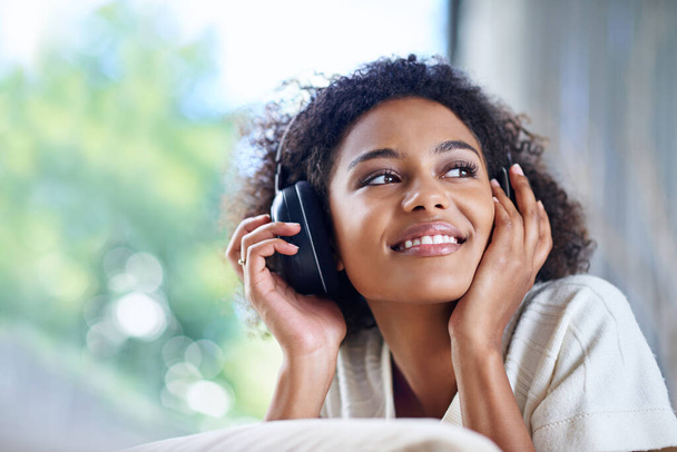 Shot of a young woman wearing headphones listening to music at home. - Foto, Imagen