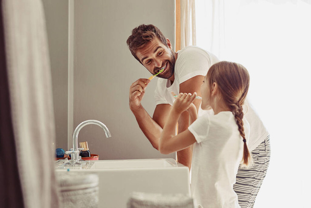 Egy boldog apa és a kislánya együtt mossák a kezüket a fürdőszobában.. - Fotó, kép